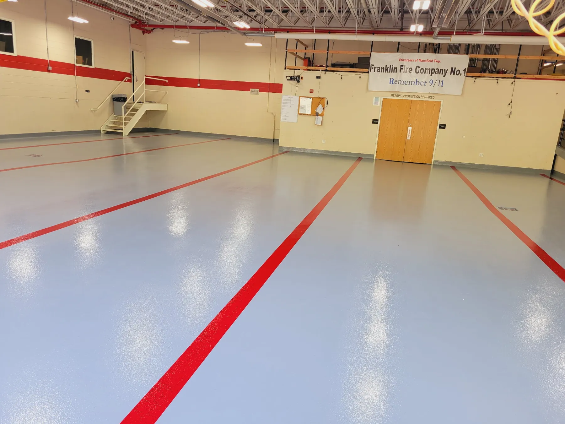 Gray epoxy firehouse bay floor with red lines marking the truck bays