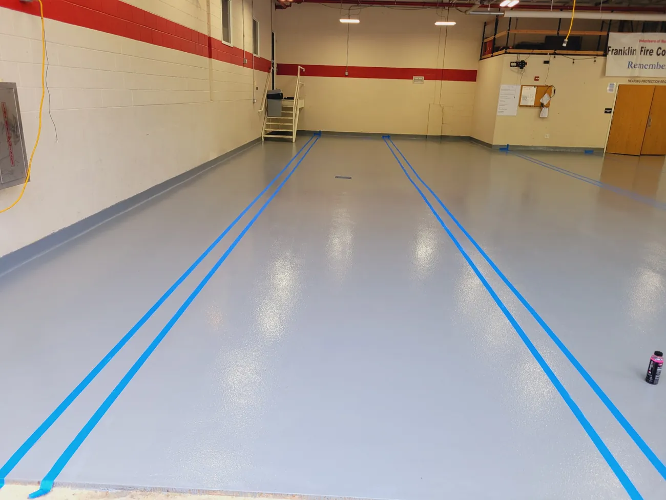 Gray epoxy floor with blue double lines in a firehouse bay