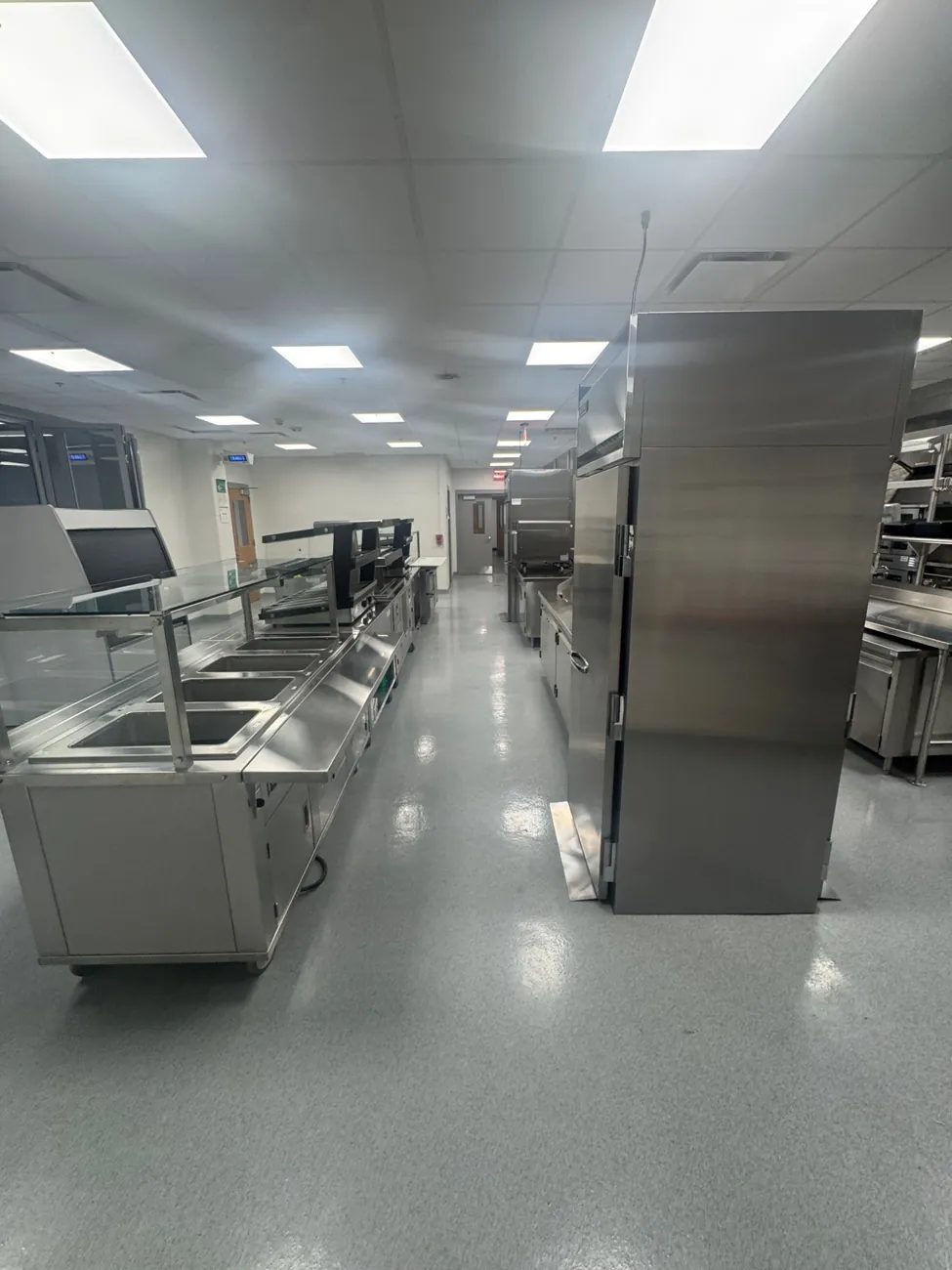 Wide view of the college kitchen with a gray epoxy quartz floor between the serving line and fridges