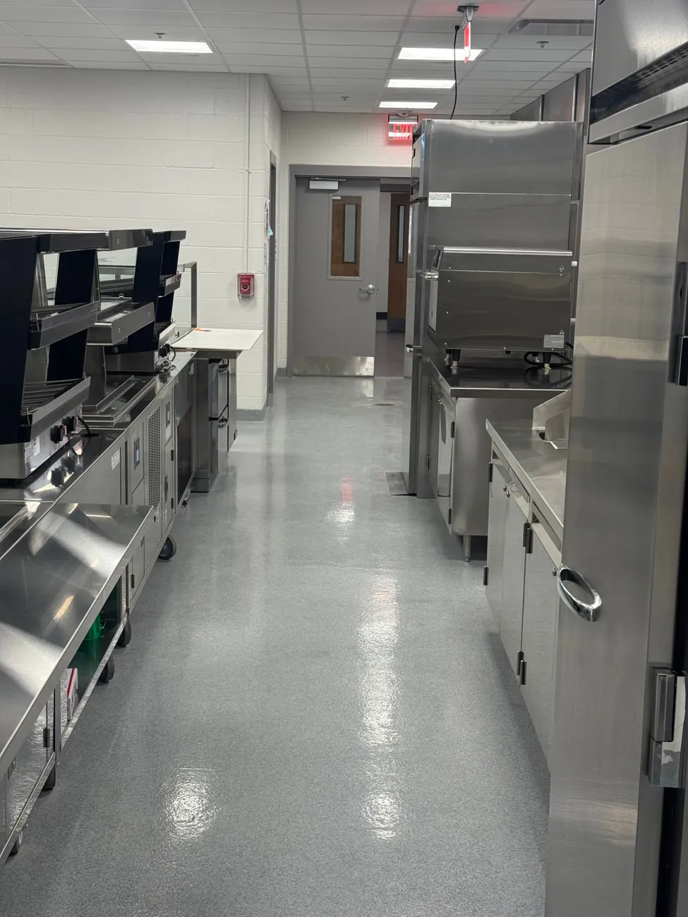 Gray epoxy quartz floor along a kitchen aisle toward the exit door