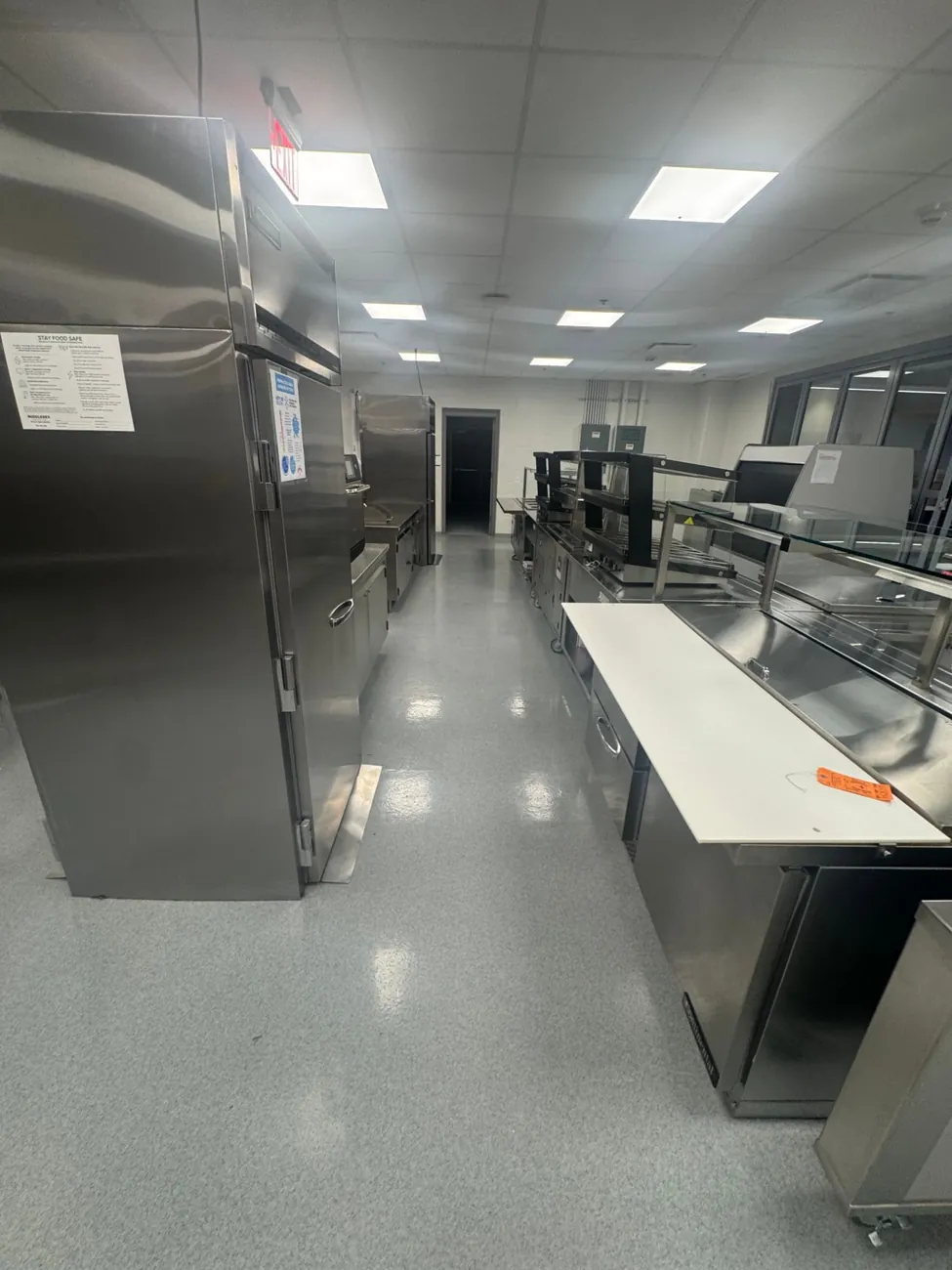 Kitchen aisle with a glossy gray quartz floor between fridges and the serving counter
