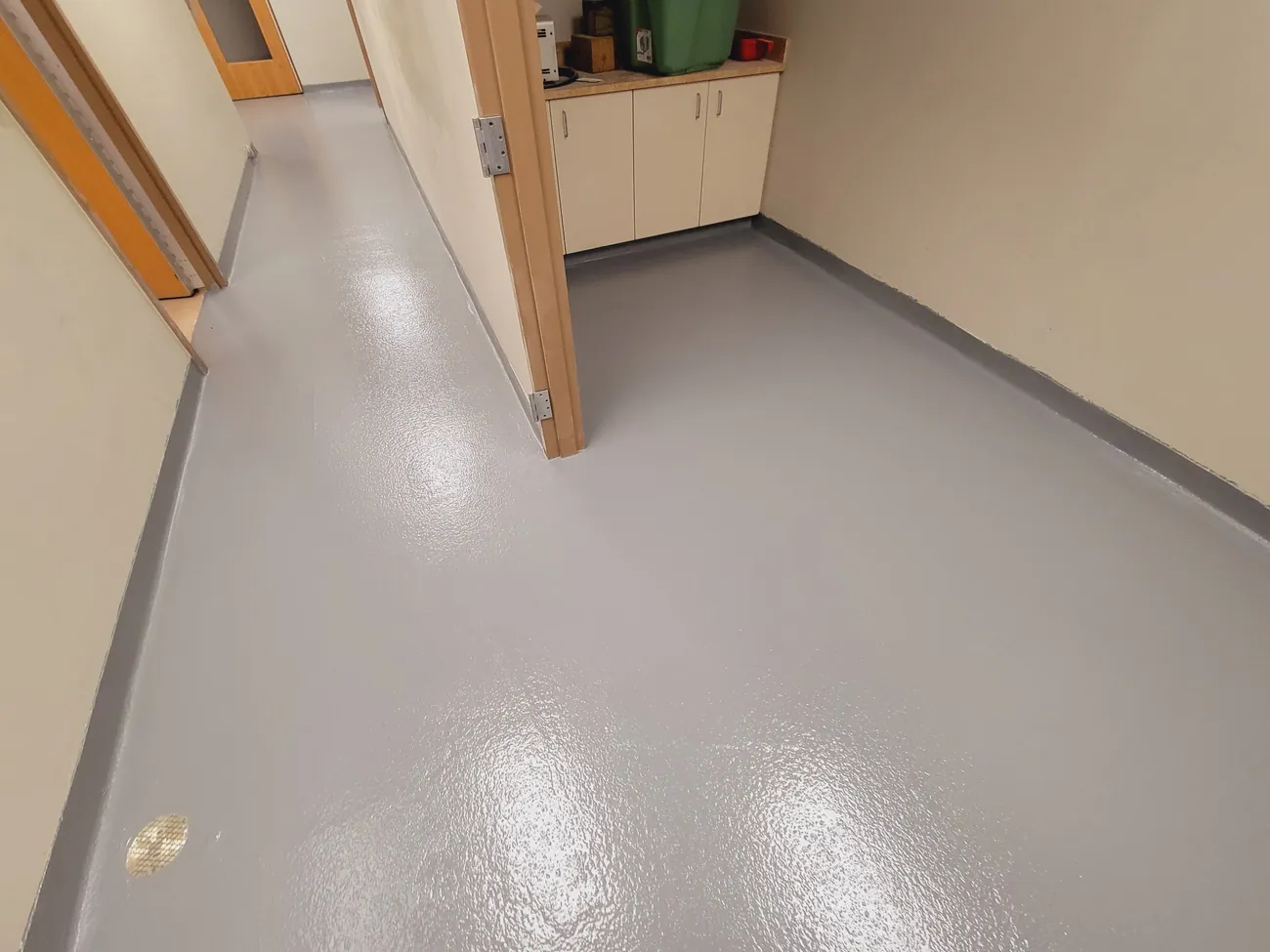 Gray epoxy floor running into a kitchenette area